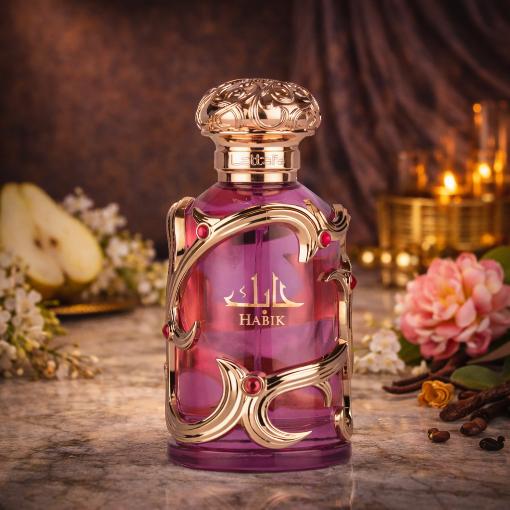 Eau de Parfum Lattafa “Habik” in una bottiglia di vetro viola con dettagli ornamentali dorati e tappo color rosa, presentata su una superficie in marmo con pera, fiori bianchi, fiori rosa, spezie e una calda luce di candela sullo sfondo.